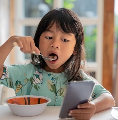 crianca comendo com celular